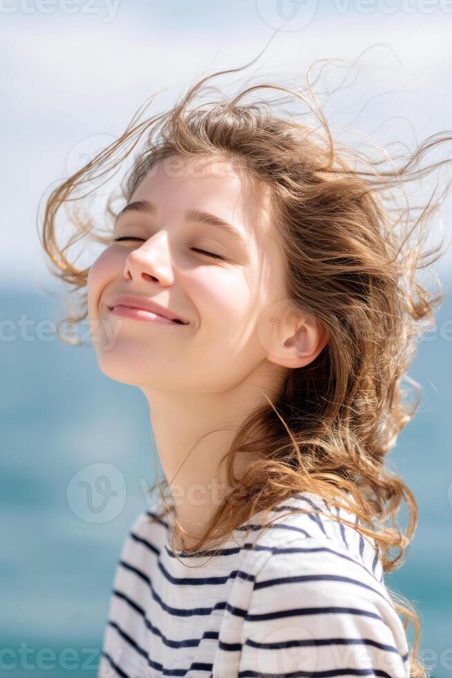 Young woman enjoying summer wind with closed eyes and smiling face photo