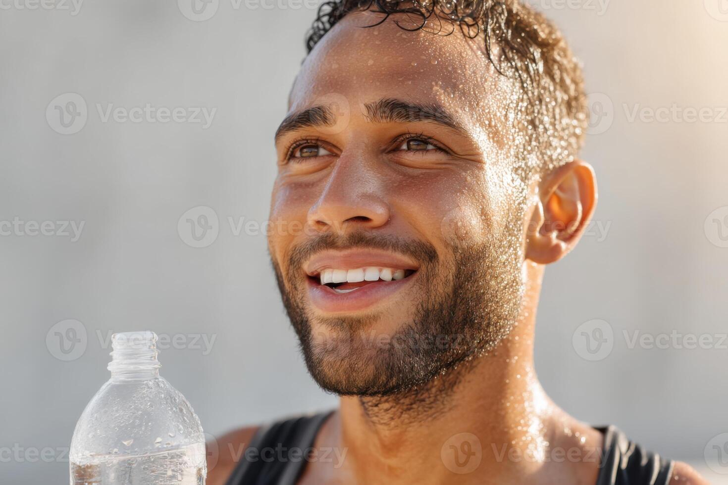 Happy athlete smiling and holding water bottle after training photo