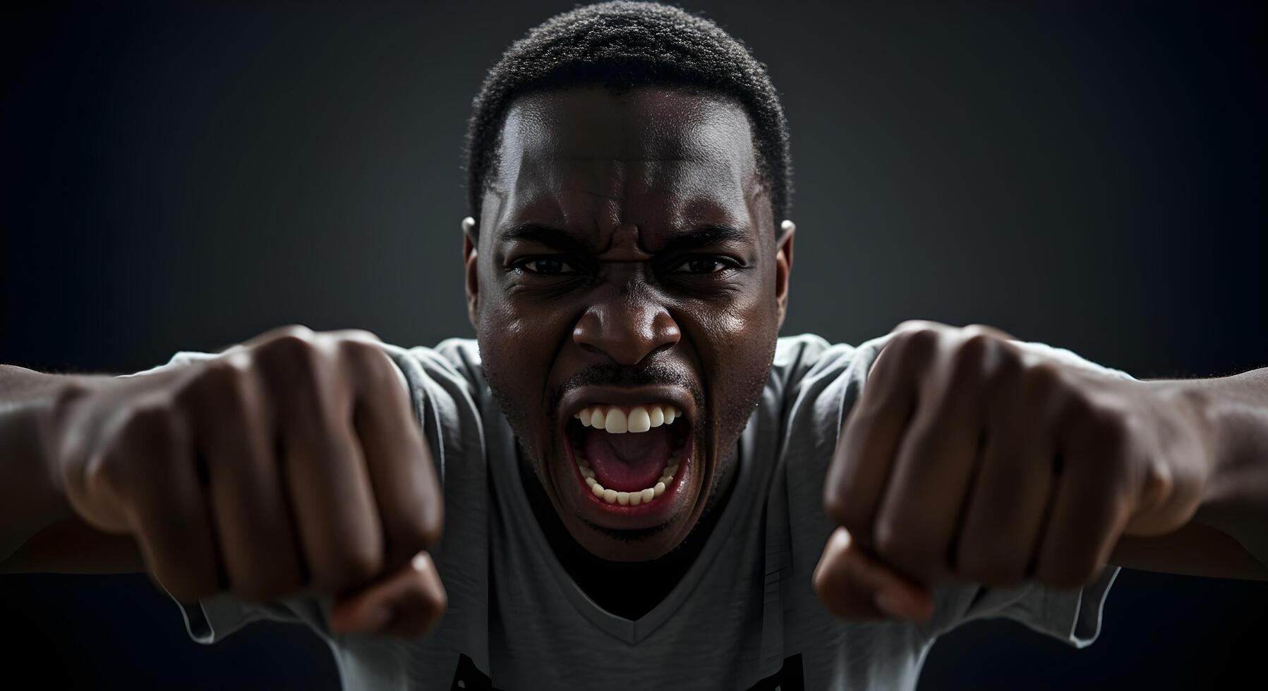 Man expresses intense emotion with clenched fists and a fierce scream in a dark setting photo