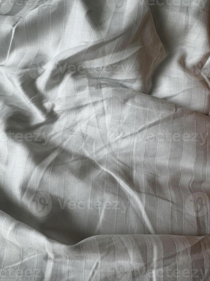 Soft white fabric draped elegantly on a surface creating gentle folds and shadows photo