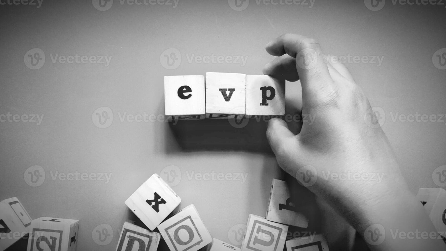 Man holding wooden cube with EVP written on it, Employee Value Proposition concept isolated on a dark background. photo