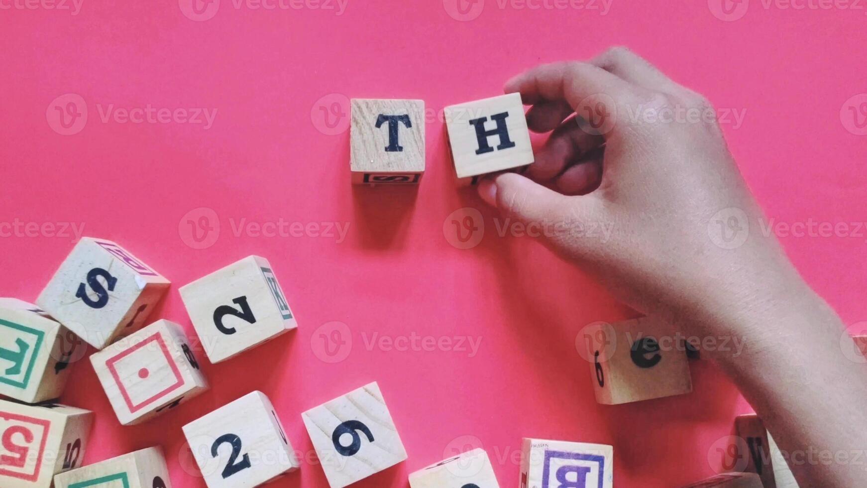 Man holding wooden cubes labeled TH or Town Hall isolated on a red background. A town hall is a forum or open meeting that aims to discuss, share information and exchange ideas. photo