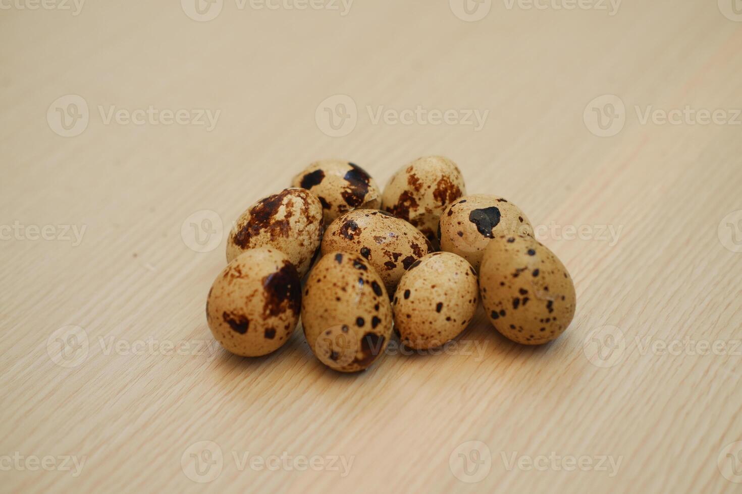 a cluster of quail eggs placed on a light wooden surface photo