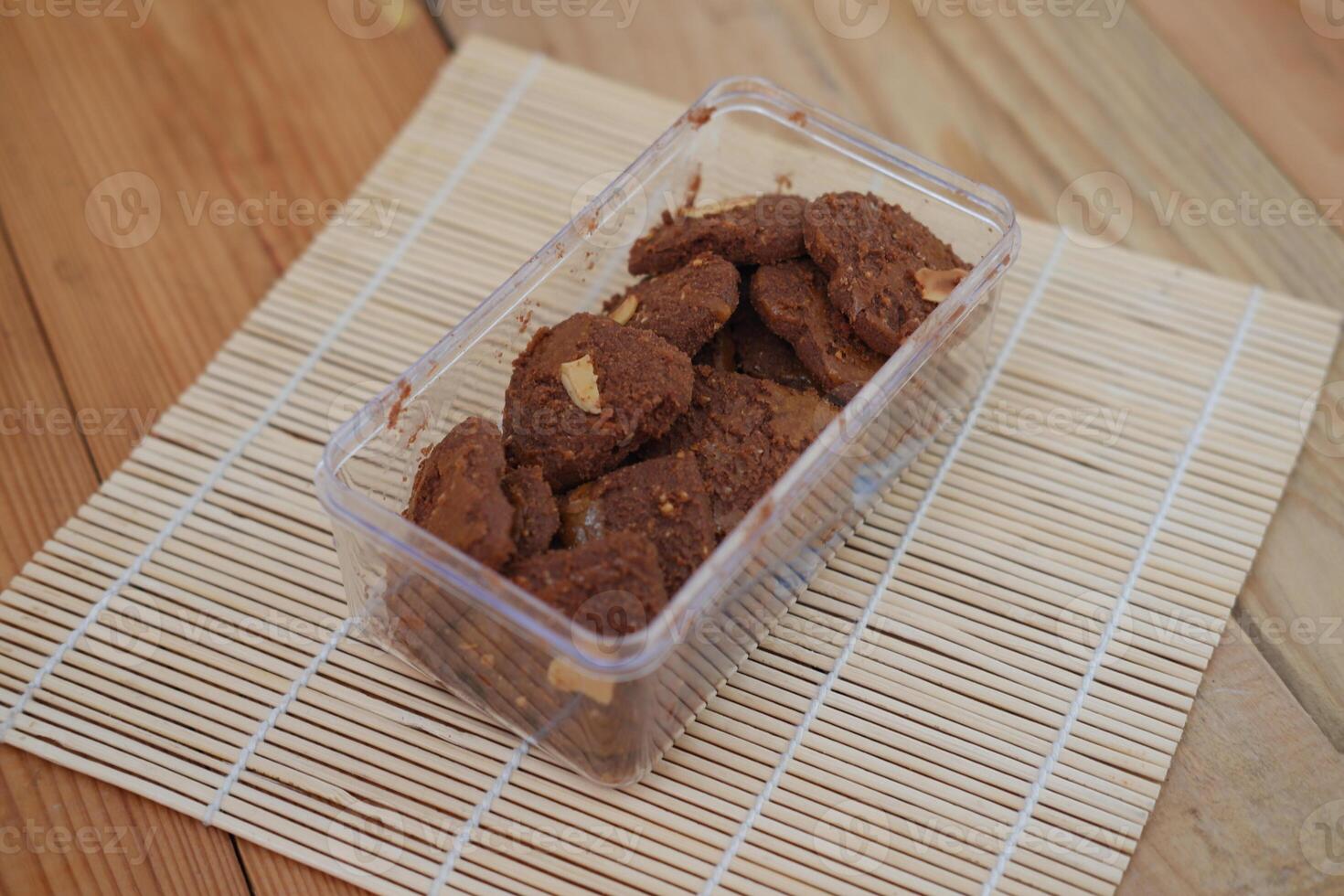 A clear plastic container holds a batch of rustic looking chocolate cookies photo