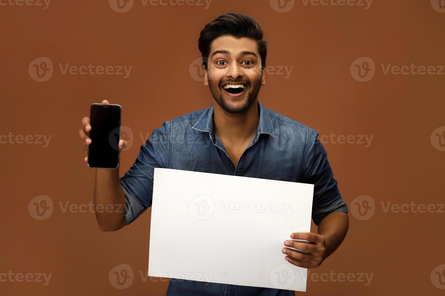 Young Indian model holding a banner and cell phone is posing for a commercial ad. photo