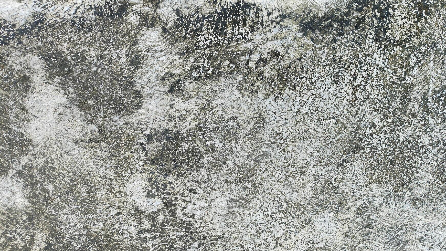 A weathered concrete wall with moss growing on the plaster cement, showcasing signs of age, nature, and decay, offering a rustic, natural aesthetic photo