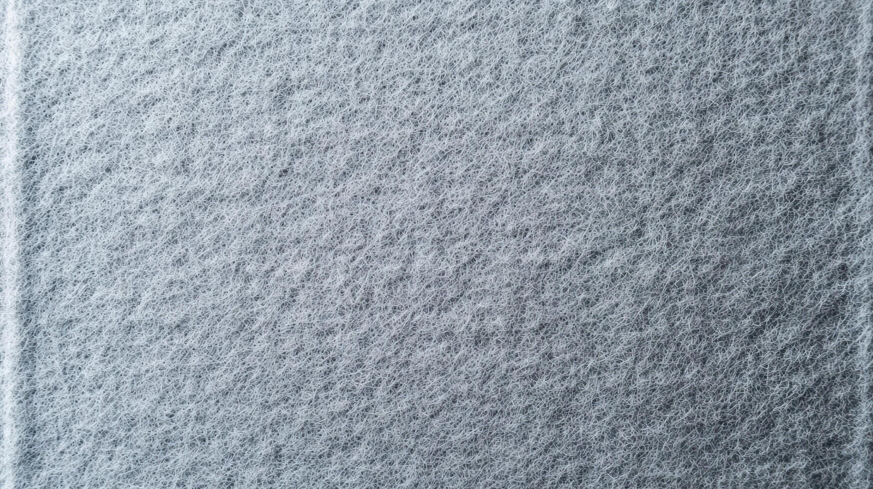 Close Up Gray Felt Texture Surface showing tangled synthetic fibers with porous structure and fine thread pattern resembling industrial felt for textile or material design backgrounds. photo