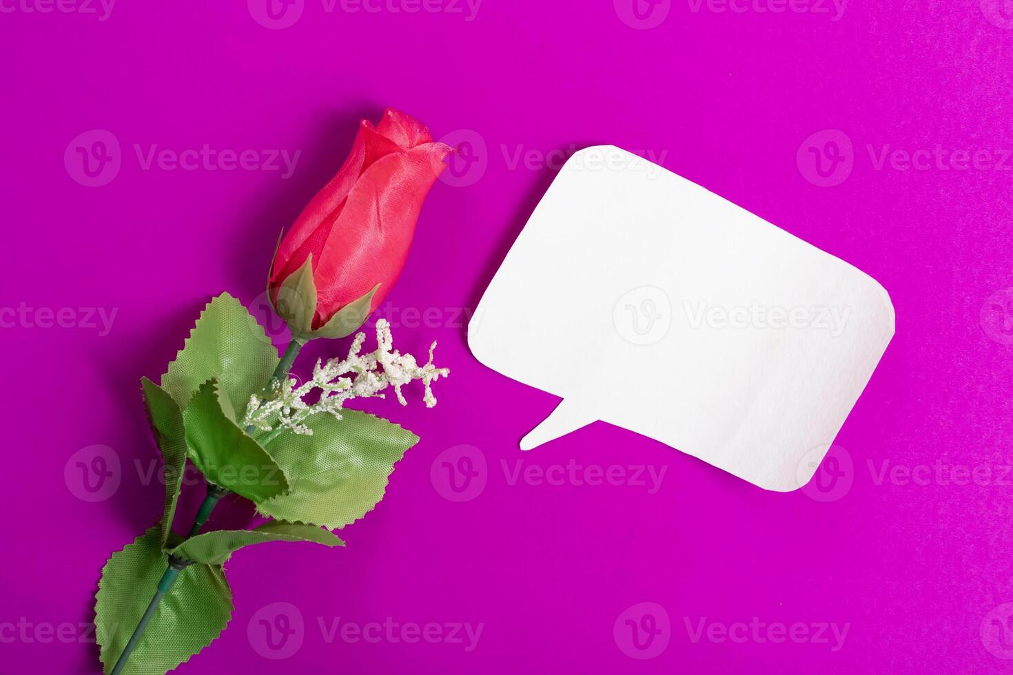 Artificial red rose with blank speech bubble on vibrant pink background. photo