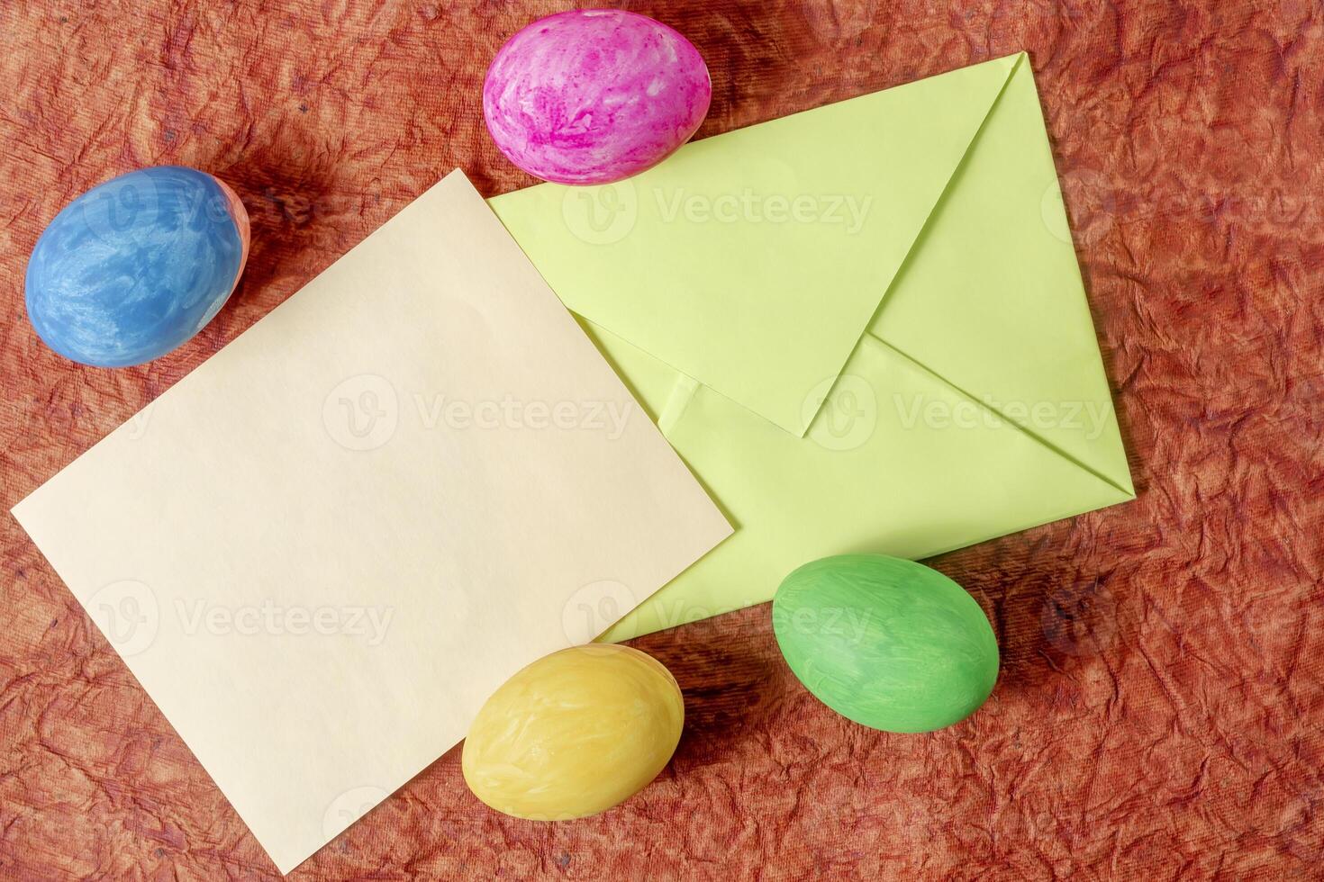 Colorful Easter eggs, envelope and blank card on textured background. photo