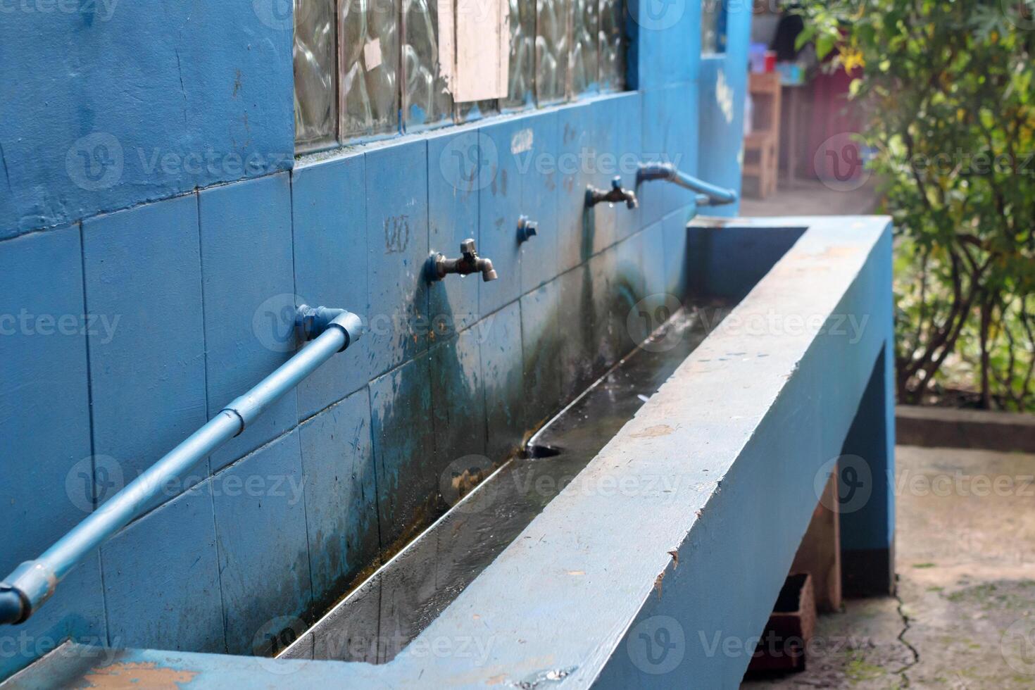 Public hand wash station with old water taps in outdoor hygiene area photo