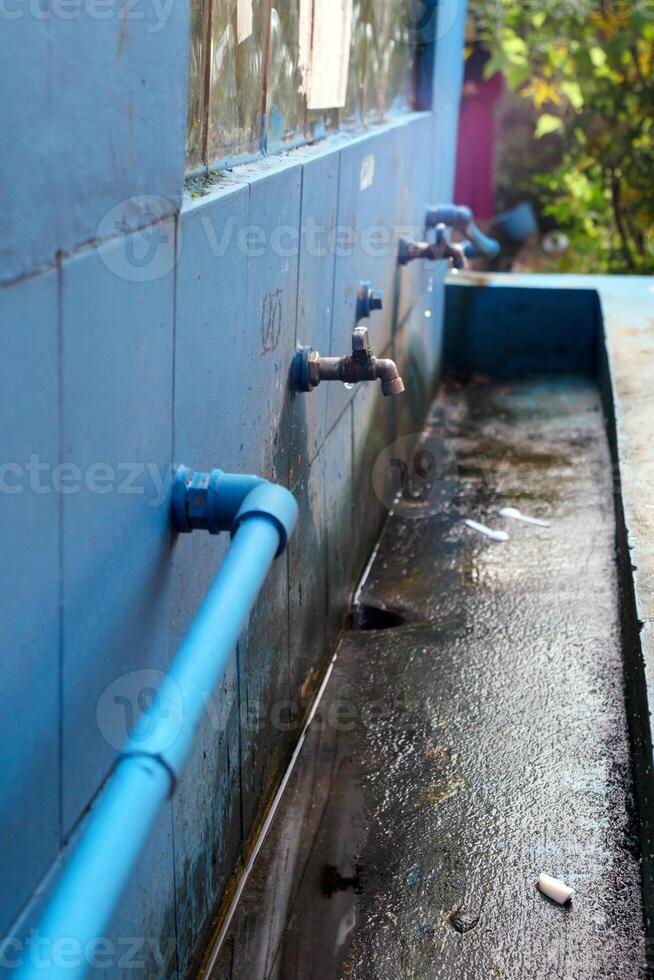 Outdoor plumbing system with water faucets line in public wash station photo