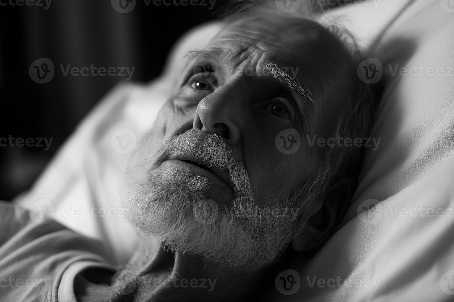Elderly man in hospital bed gazes thoughtfully during late night hours photo