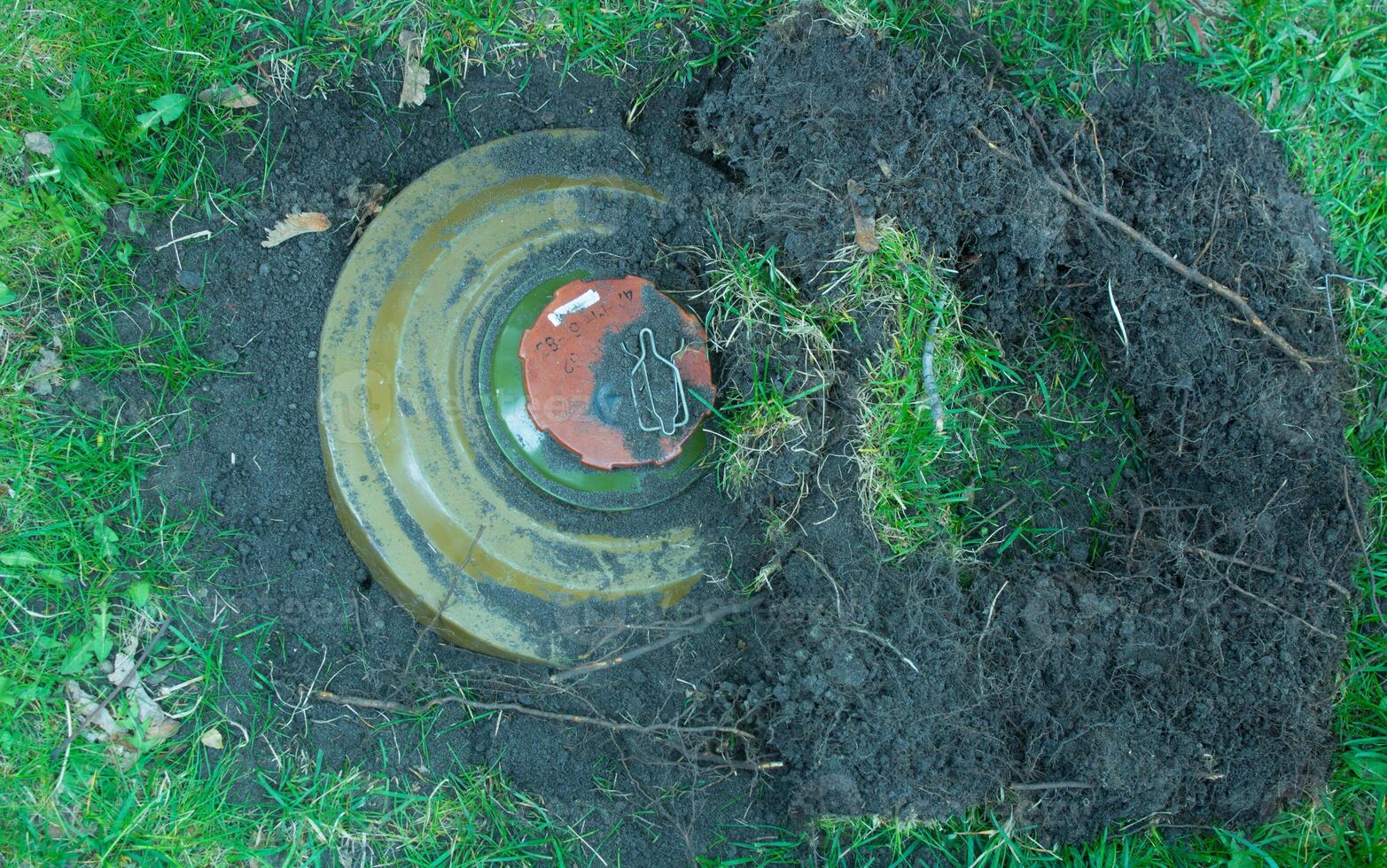 Green anti tank mine on the grass in the ground. photo