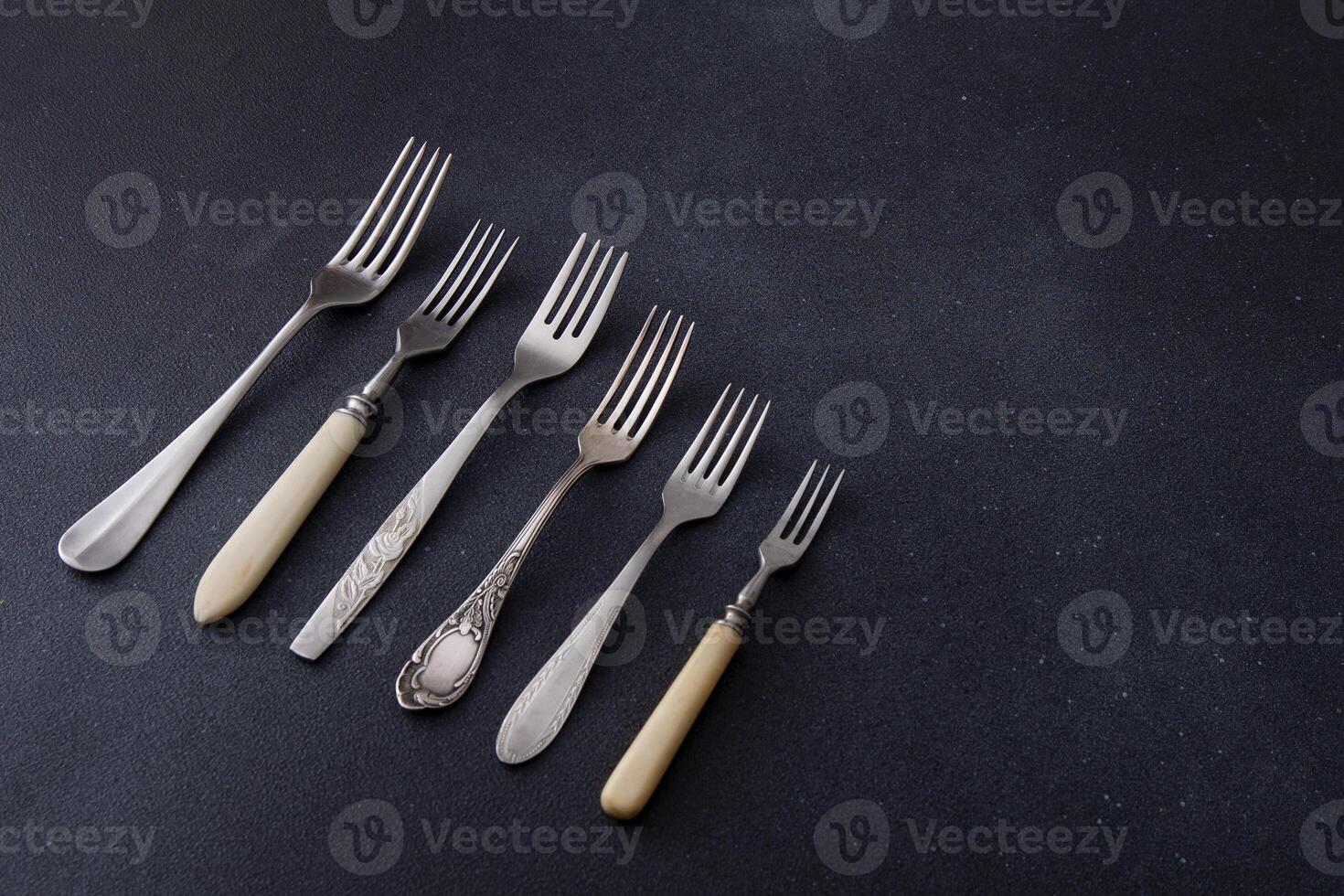 Forks on a black background. Set of old different cutlery for food. photo