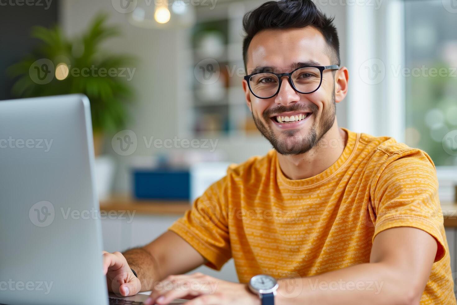 A man wearing glasses sitting at a desk using a laptop computer photo