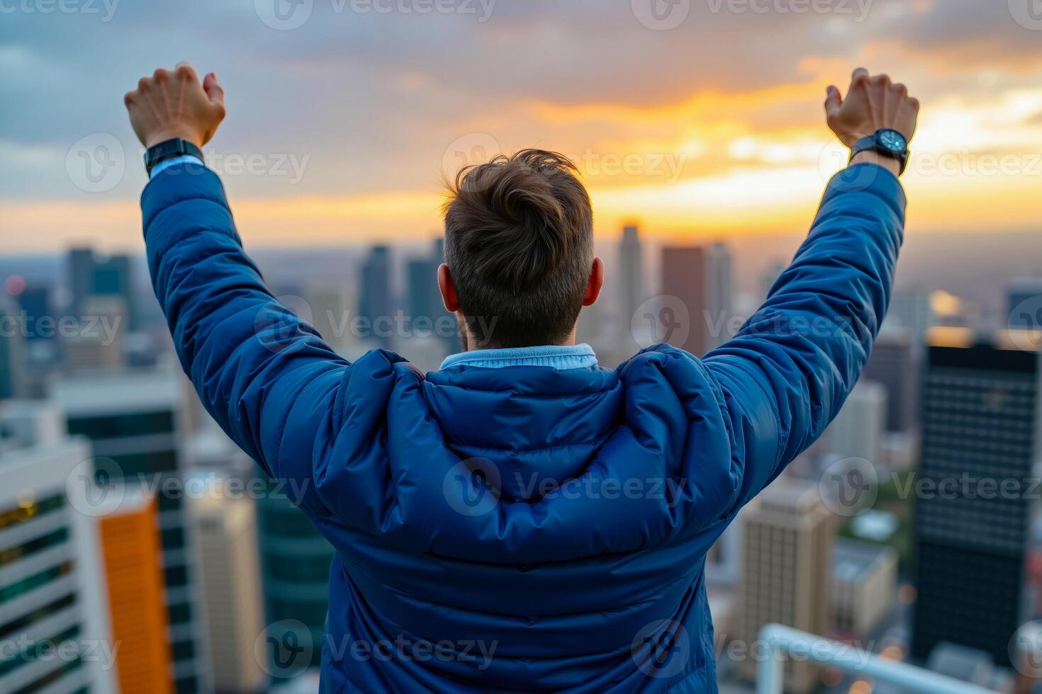 A man standing on top of a building with his arms raised in the air photo