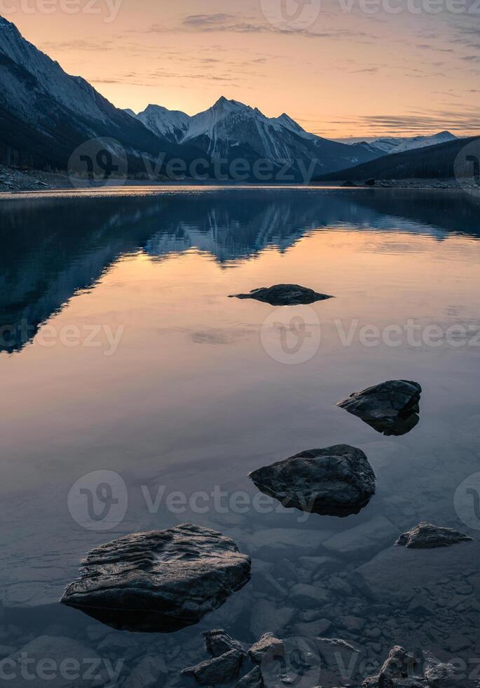 Sunrise on rocky mountain with rocks in Medicine lake in Jasper national park photo