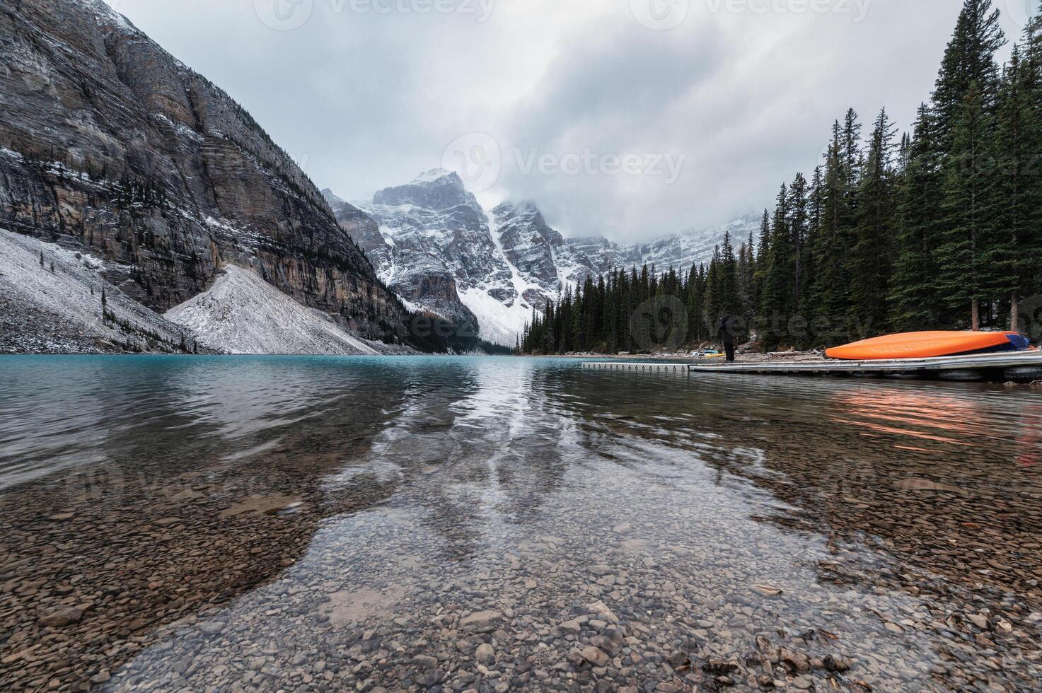 Rocky mountains with canoe on pier in Moraine Lake on gloomy at Banff national park photo