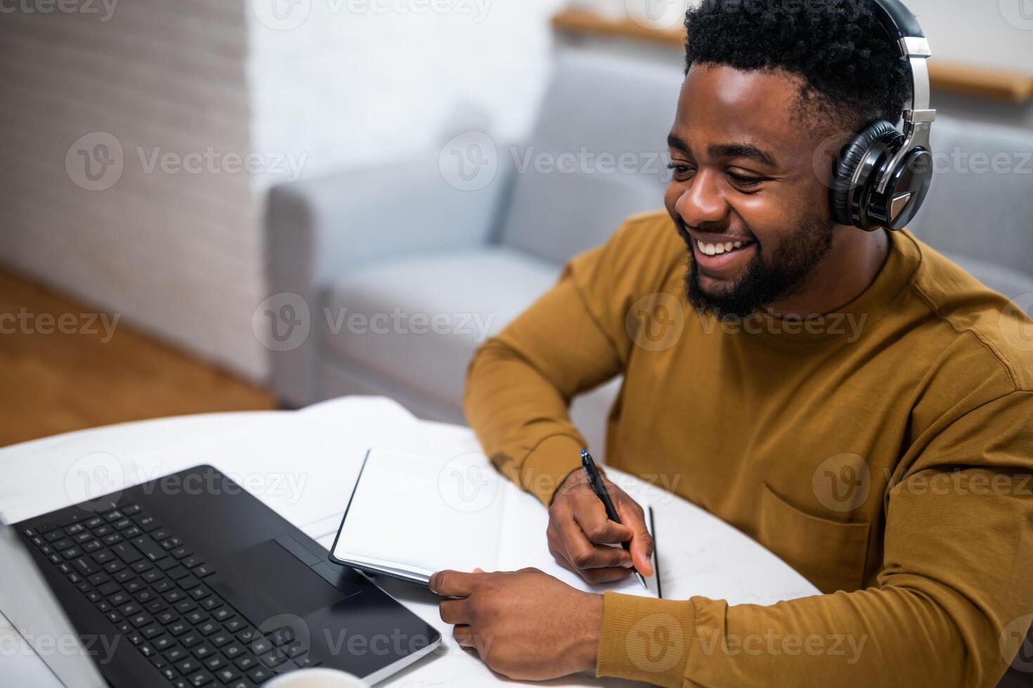 A young African American man enjoying the benefits of wireless technology as he works remotely on his laptop, participating in an online class and attending a virtual meeting. photo