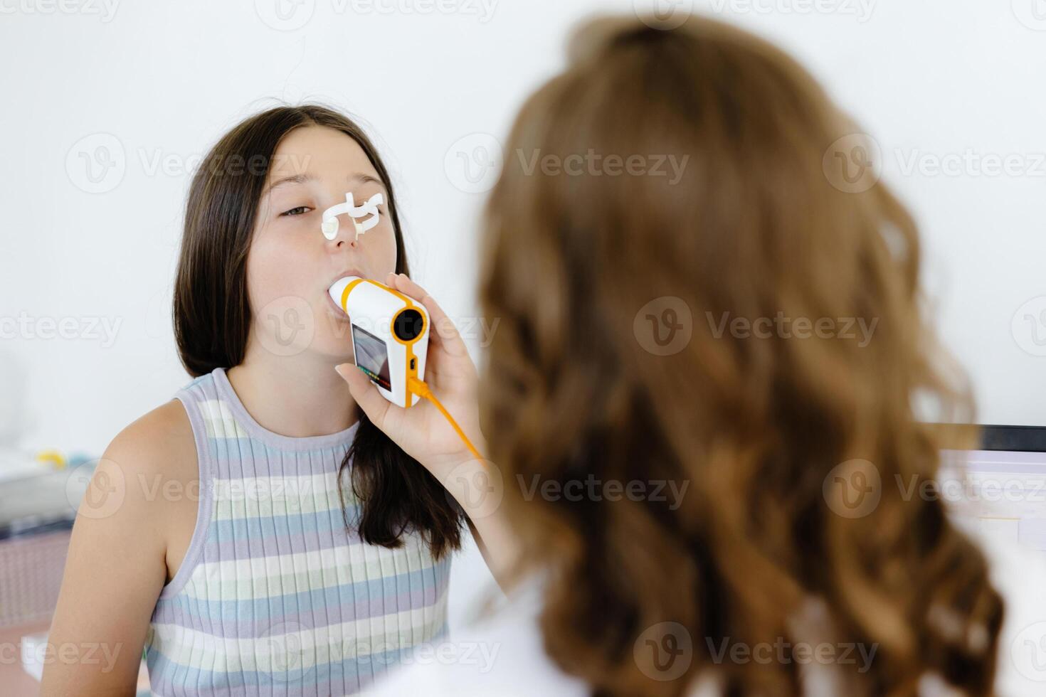 Girl testing breathing function by spirometry in doctors office. Diagnosis of respiratory function in pulmonary disease. photo