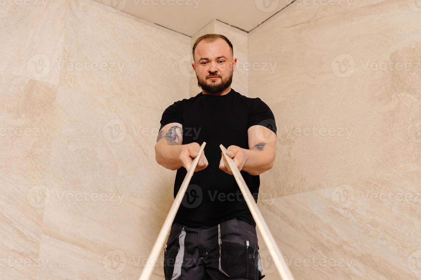 Construction worker installing ceramic tiles on bathroom wall using level tool. photo