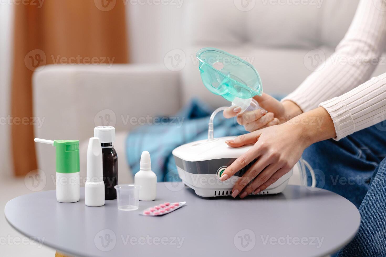 Close-up photo of sick woman with an inhaler. Unhealthy girl presses the button on the inhaler to inhale, she use nebulizer and inhaler for the treatment sitting on the couch at home