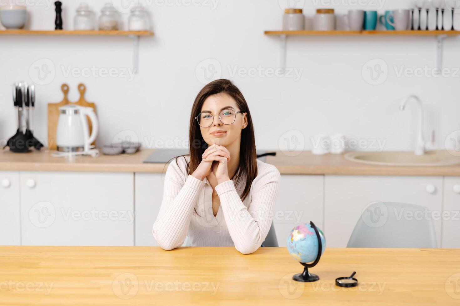 Student girl smiles, looking to camera and studies geography on a globe while sitting at home in quarantine. Education abroad. Distance learning. photo