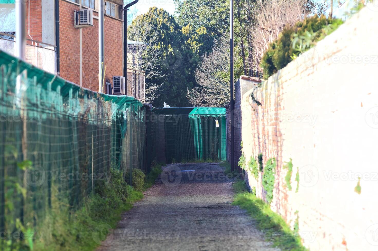 Path between a fence and a brick wall in a rural town photo