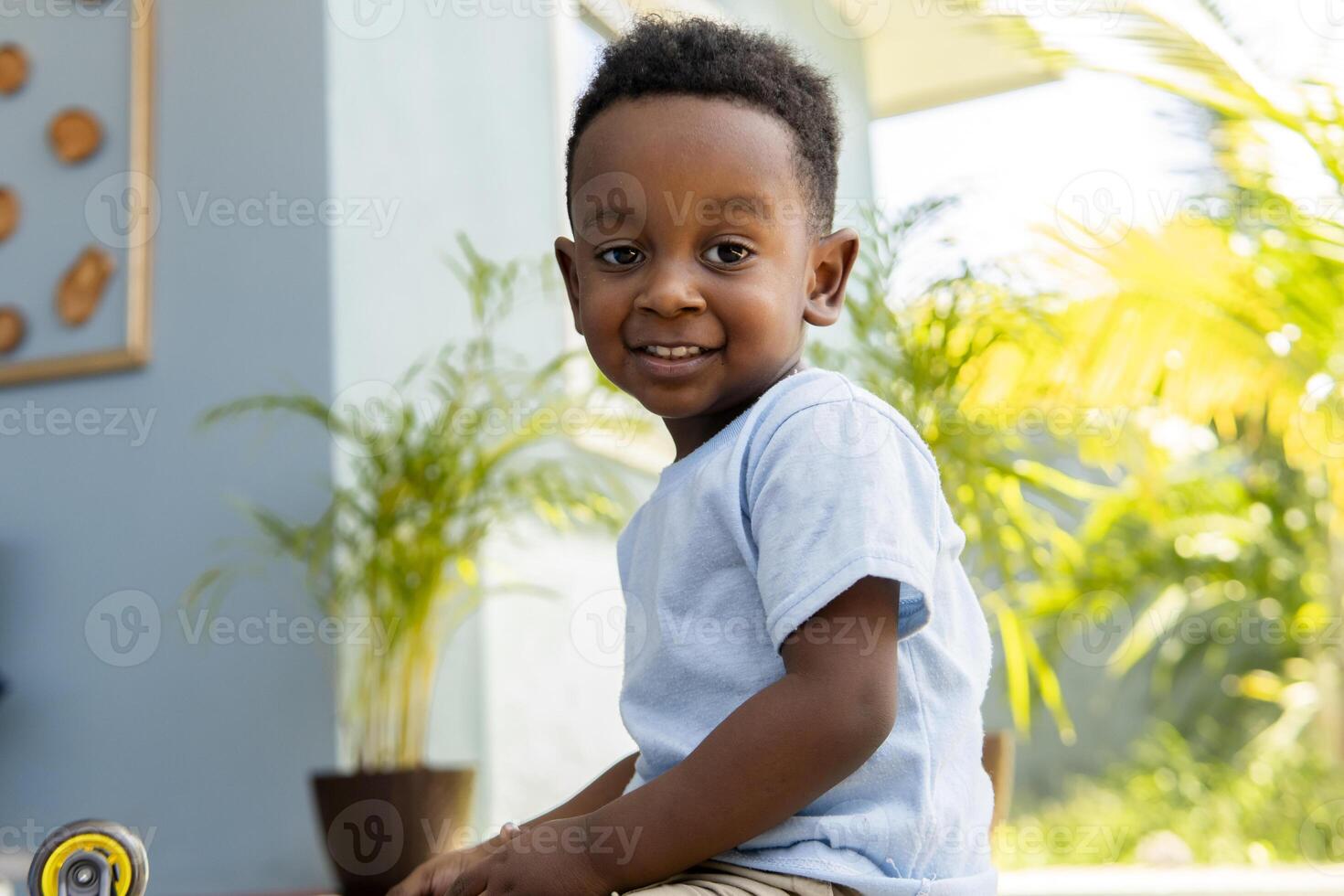 Smiling boy playing at home with plants in background photo