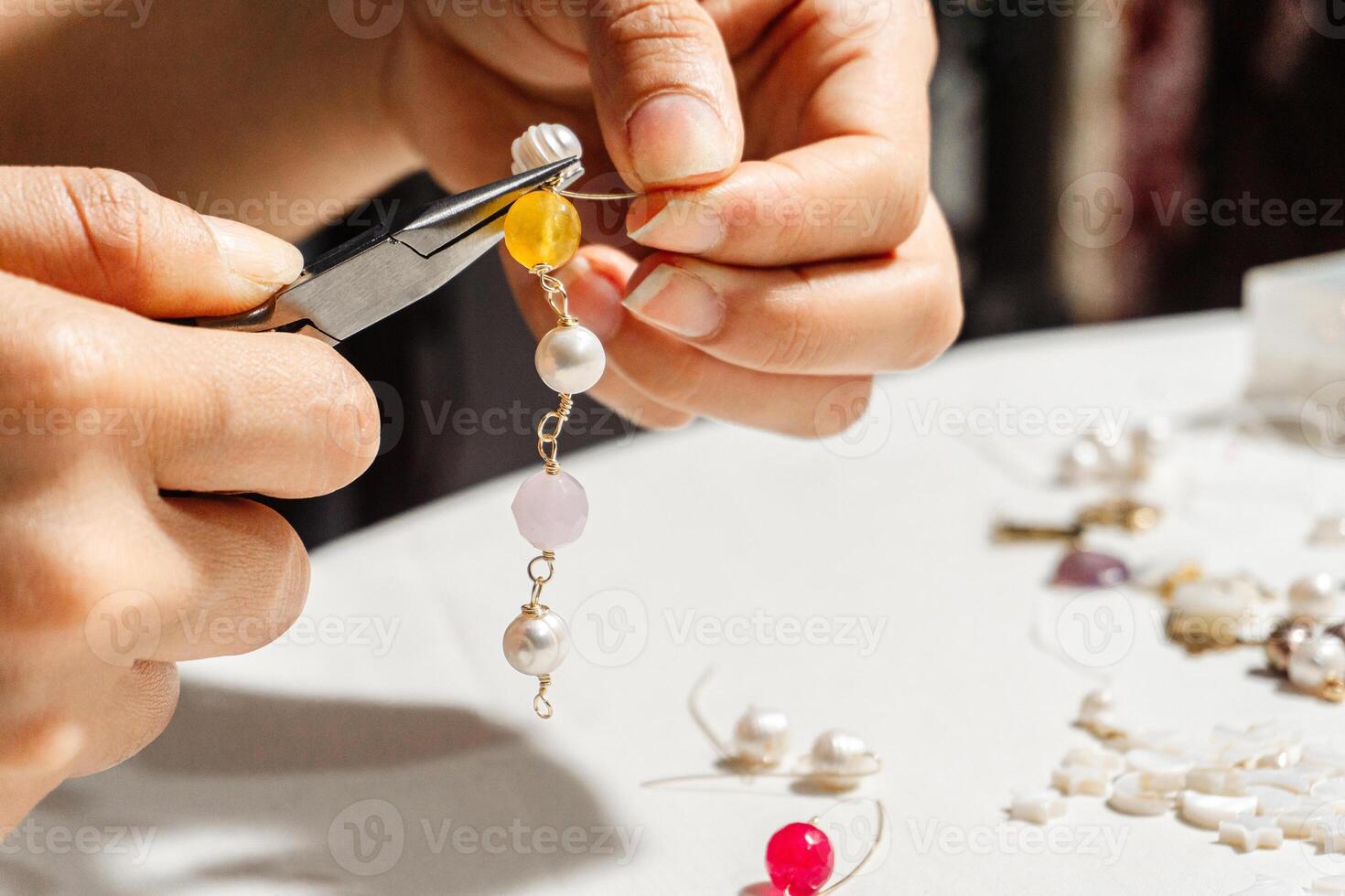 close up of a hands manipulating fine tip pliers working in a jewelry store photo