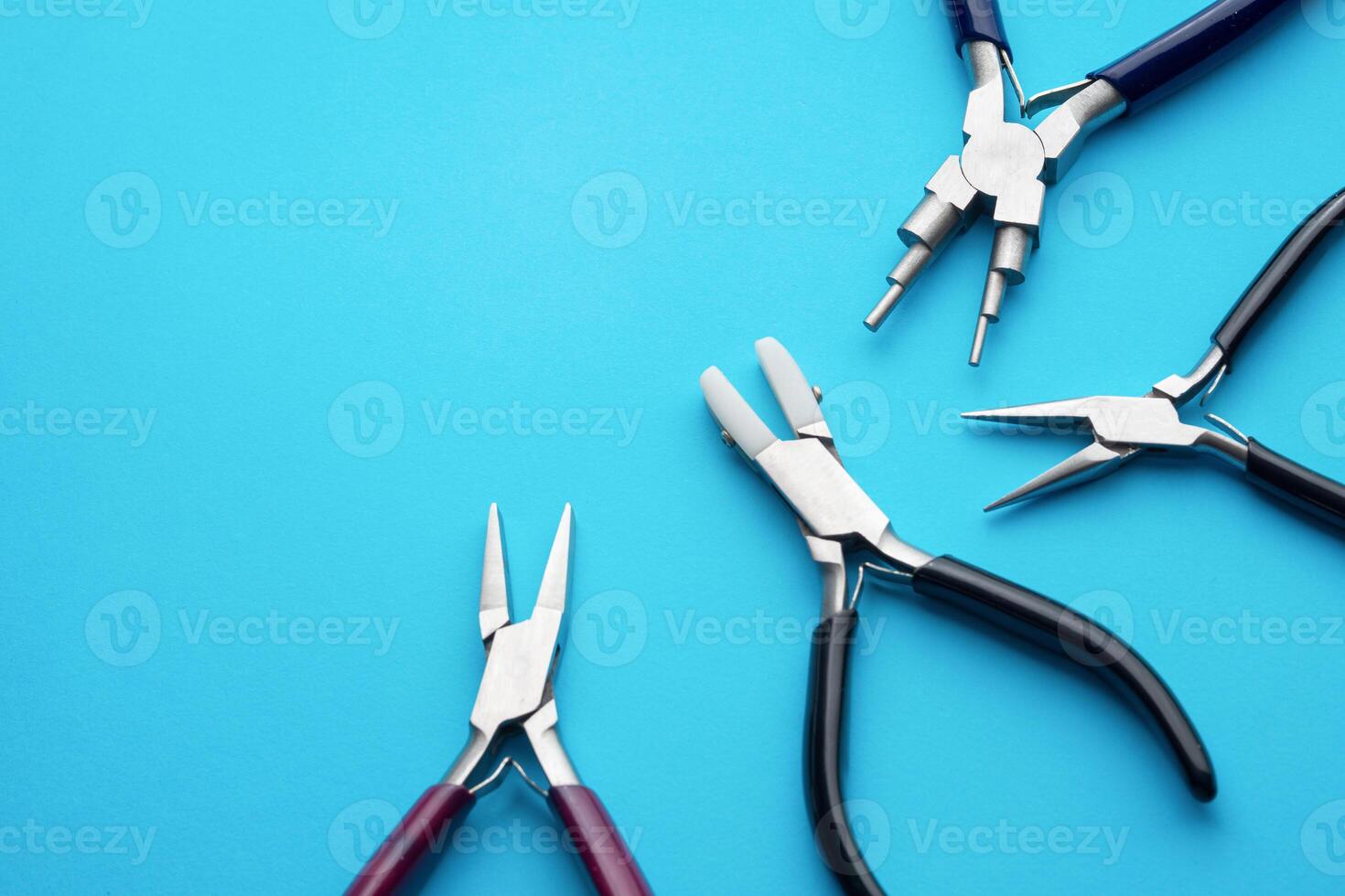 four type of pliers as tools for making imitation jewelry on isolated blue background with copy space. photo