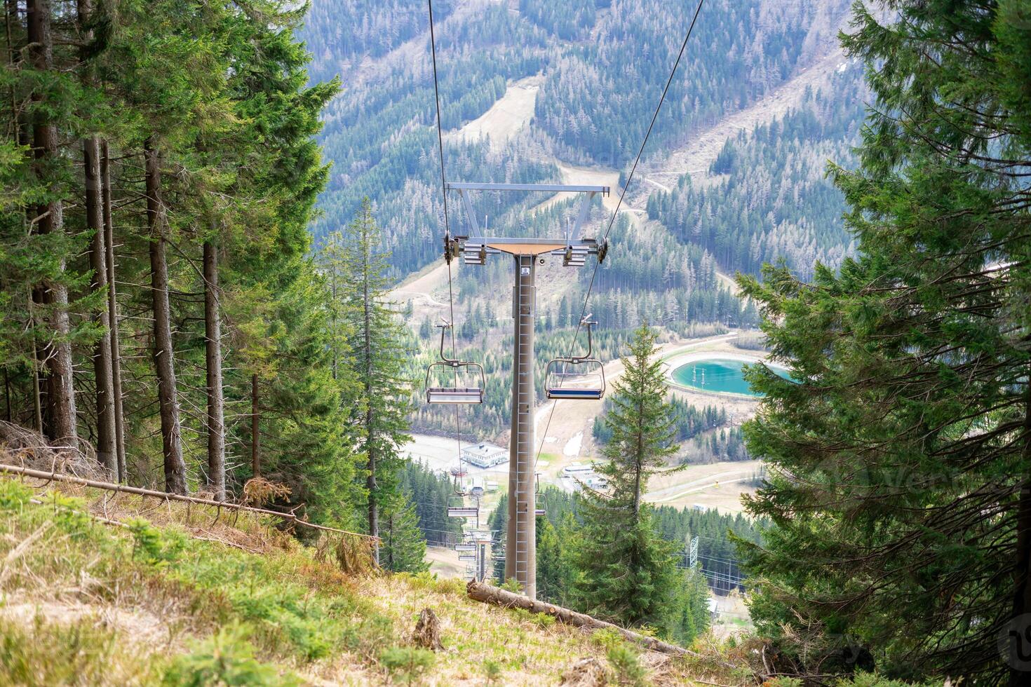 View of the cabins of the chairlift against the backdrop of mountains and forest photo