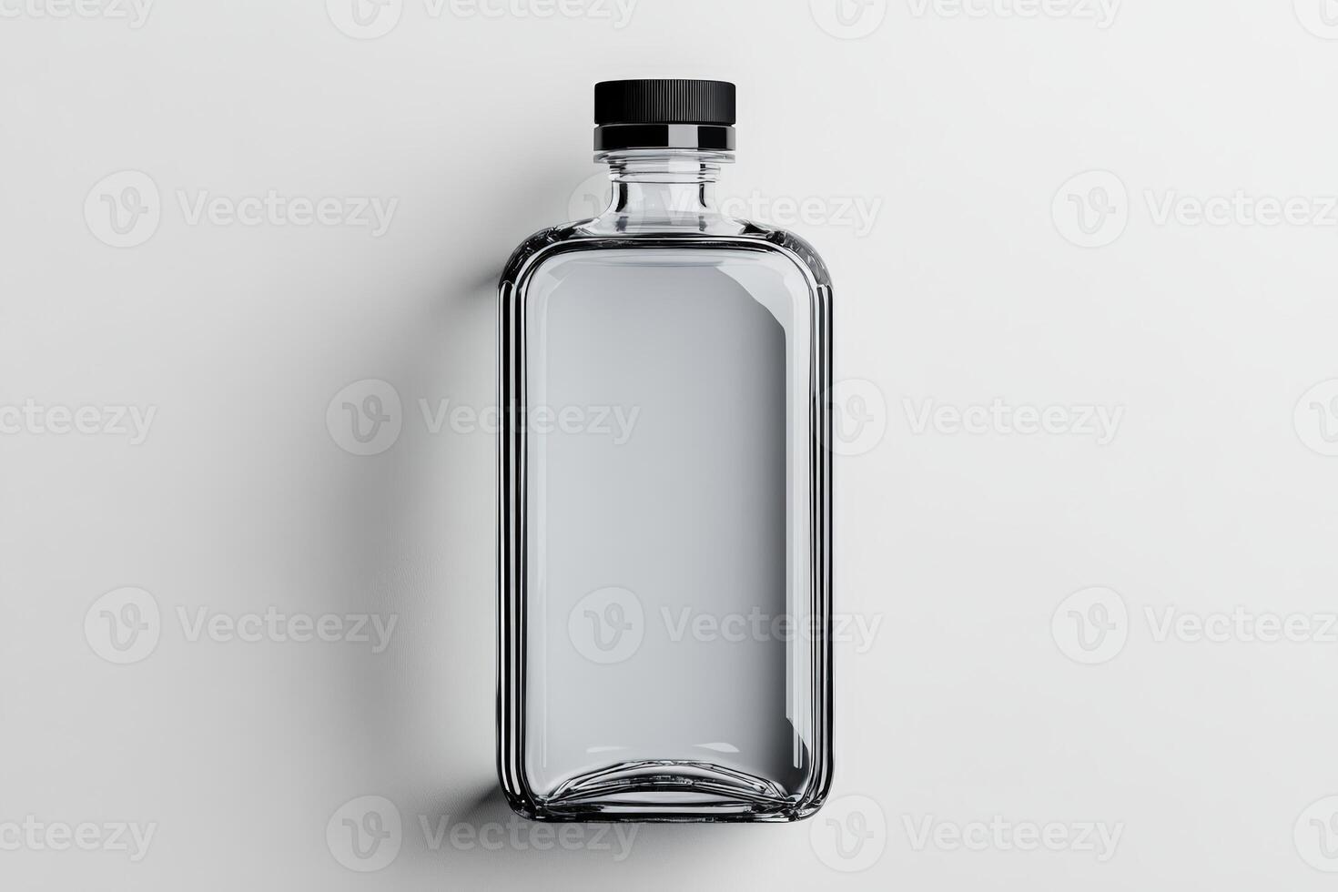 Transparent glass bottle with black cap resting on a light surface photo