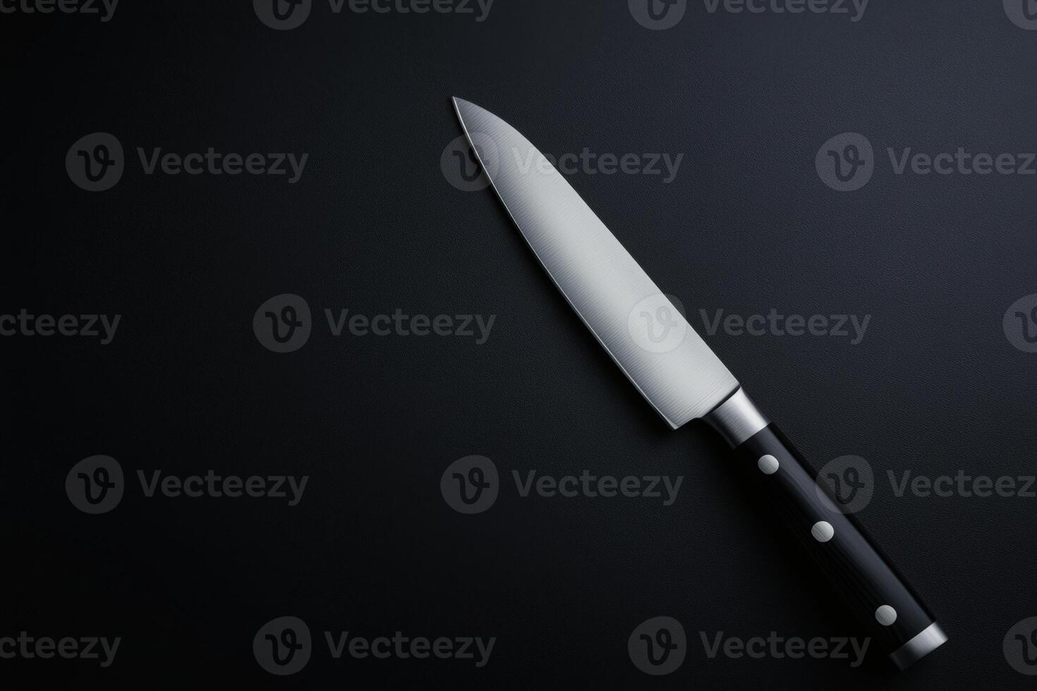 Sharp kitchen knife resting on a dark countertop ready for cooking preparation tasks photo