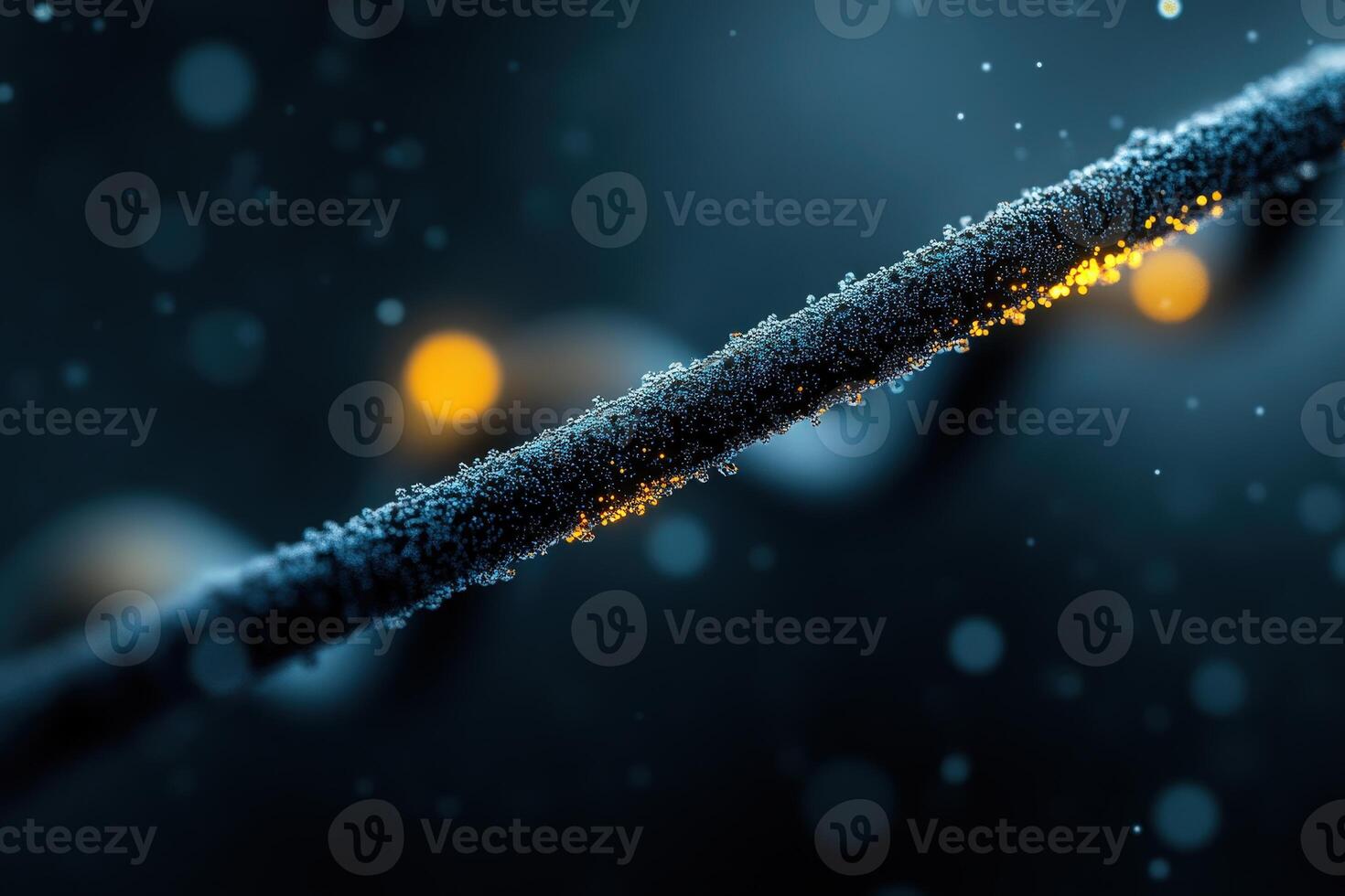 Close-up view of a textured wire covered in dew drops with glowing elements at night photo