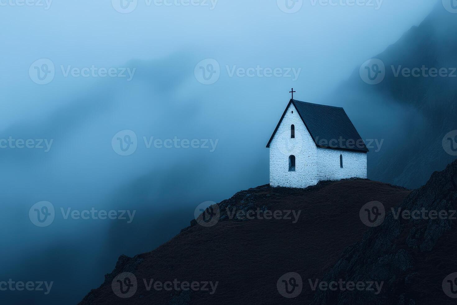 White church perched on a hilltop surrounded by misty mountains during twilight hours photo