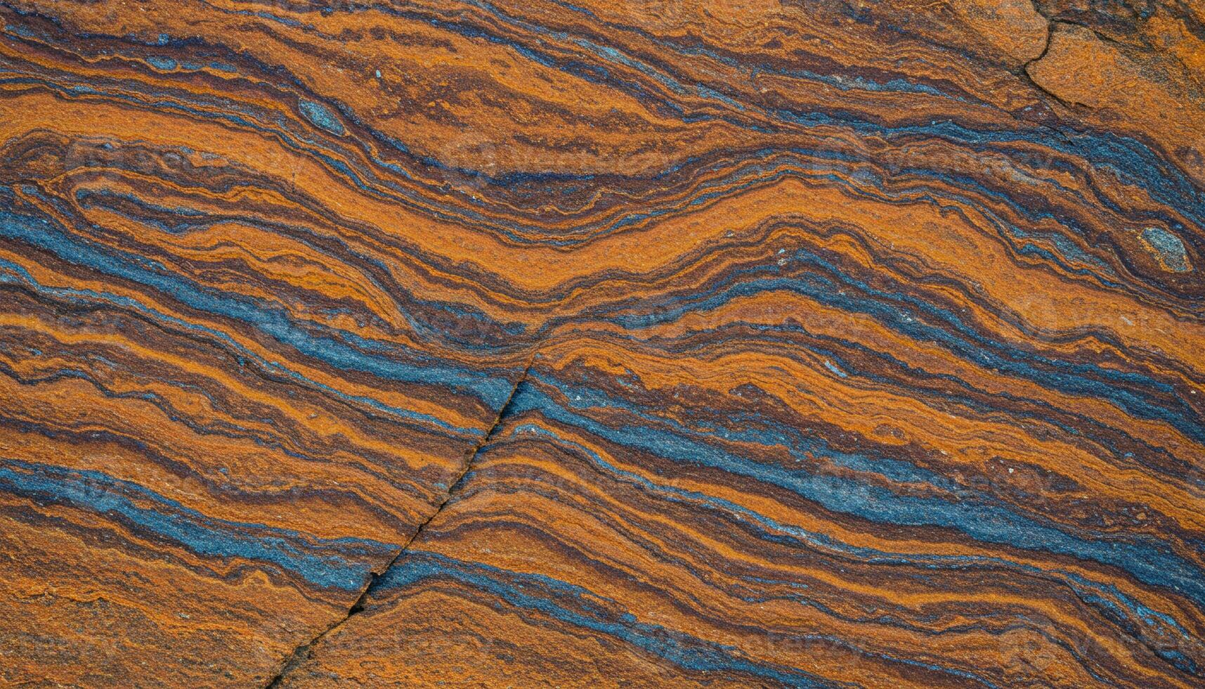 Sedimentary rock formation with orange and blue layered textures and wavy natural patterns photo