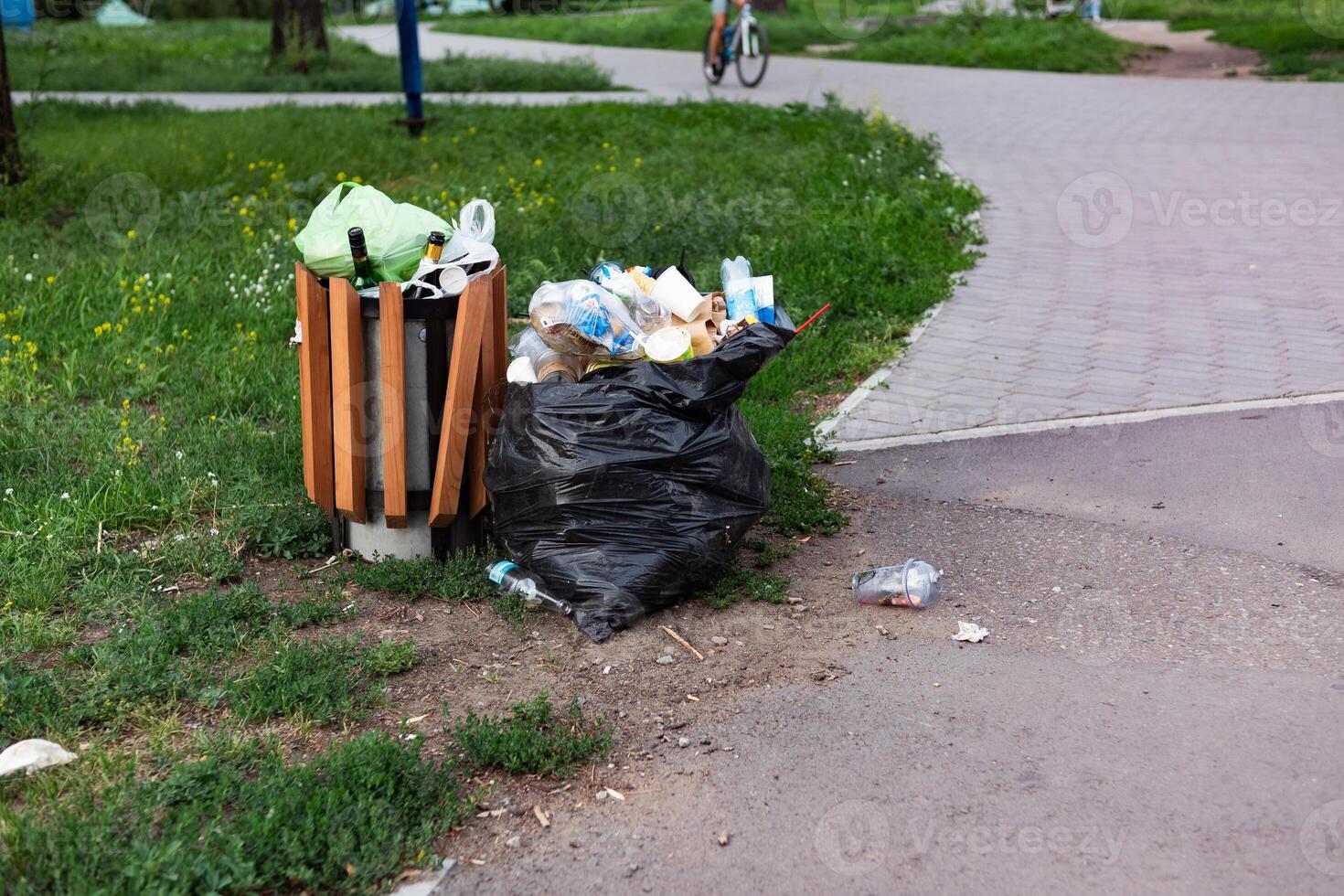 Overflowing green garbage bin in Surrey park clothe to Thames Path. photo