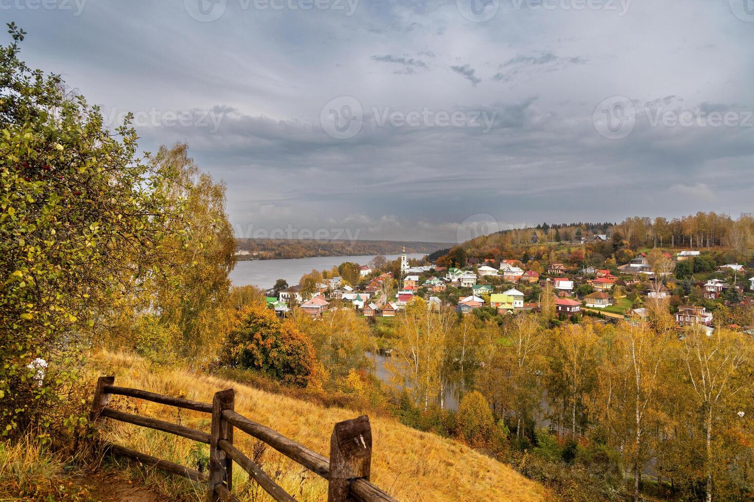 View of the autumn Plyos and Varvarinskaya church from the height of the Cathedral Mountain from behind a wooden fence photo