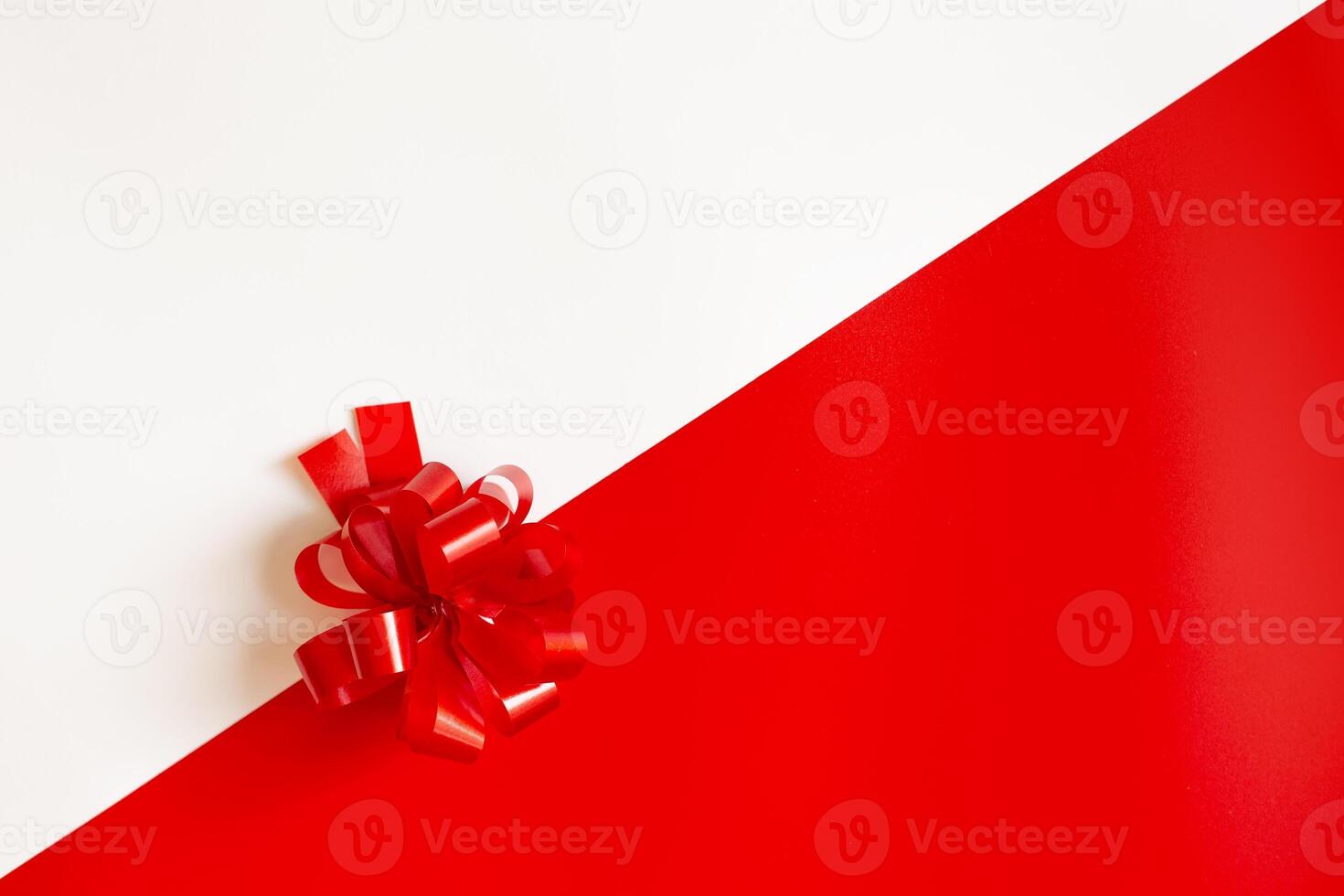 Red plastic bow on a red and white diagonal paper texture photo