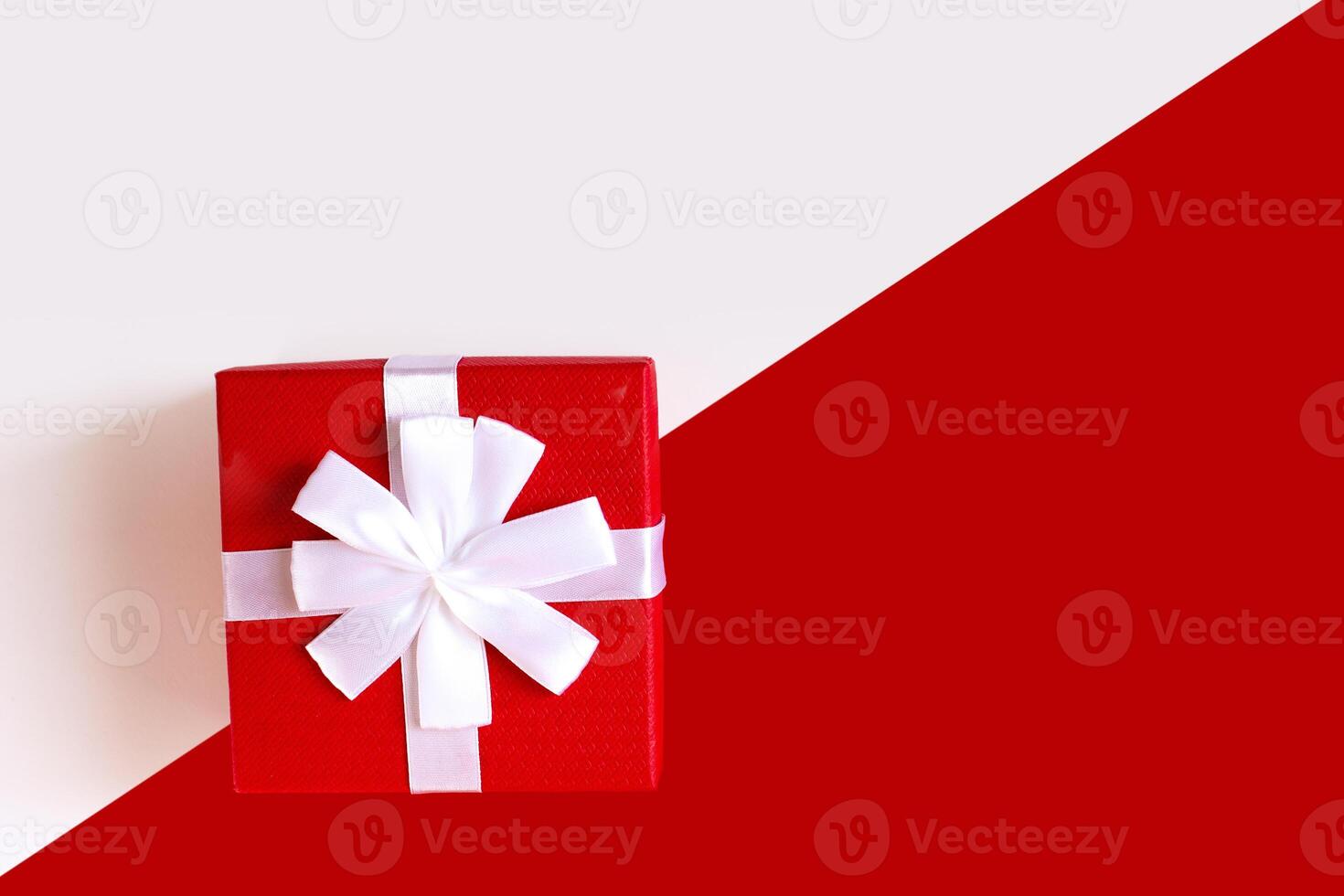 Red and white diagonal paper texture, red gift box with white bow photo