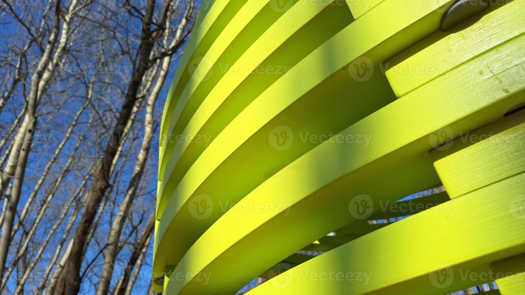 Abstract yellow structure with leafless trees against blue sky photo