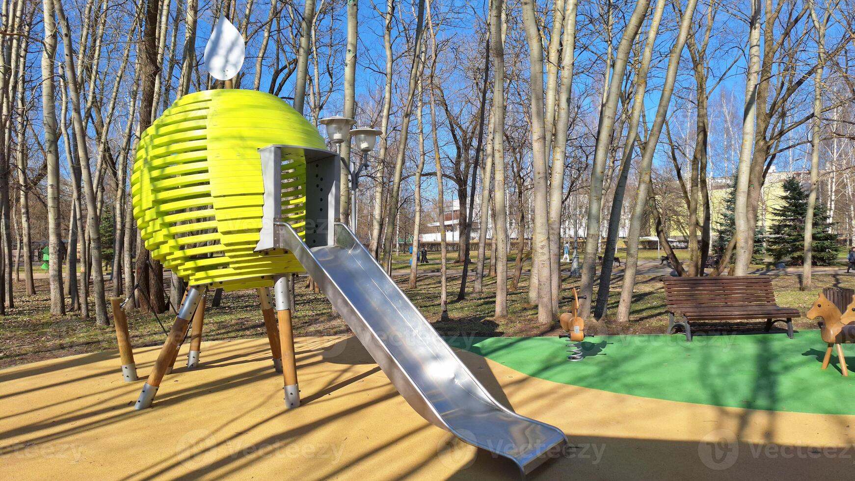 Modern playground with unique slide and spring riders in leafy park photo