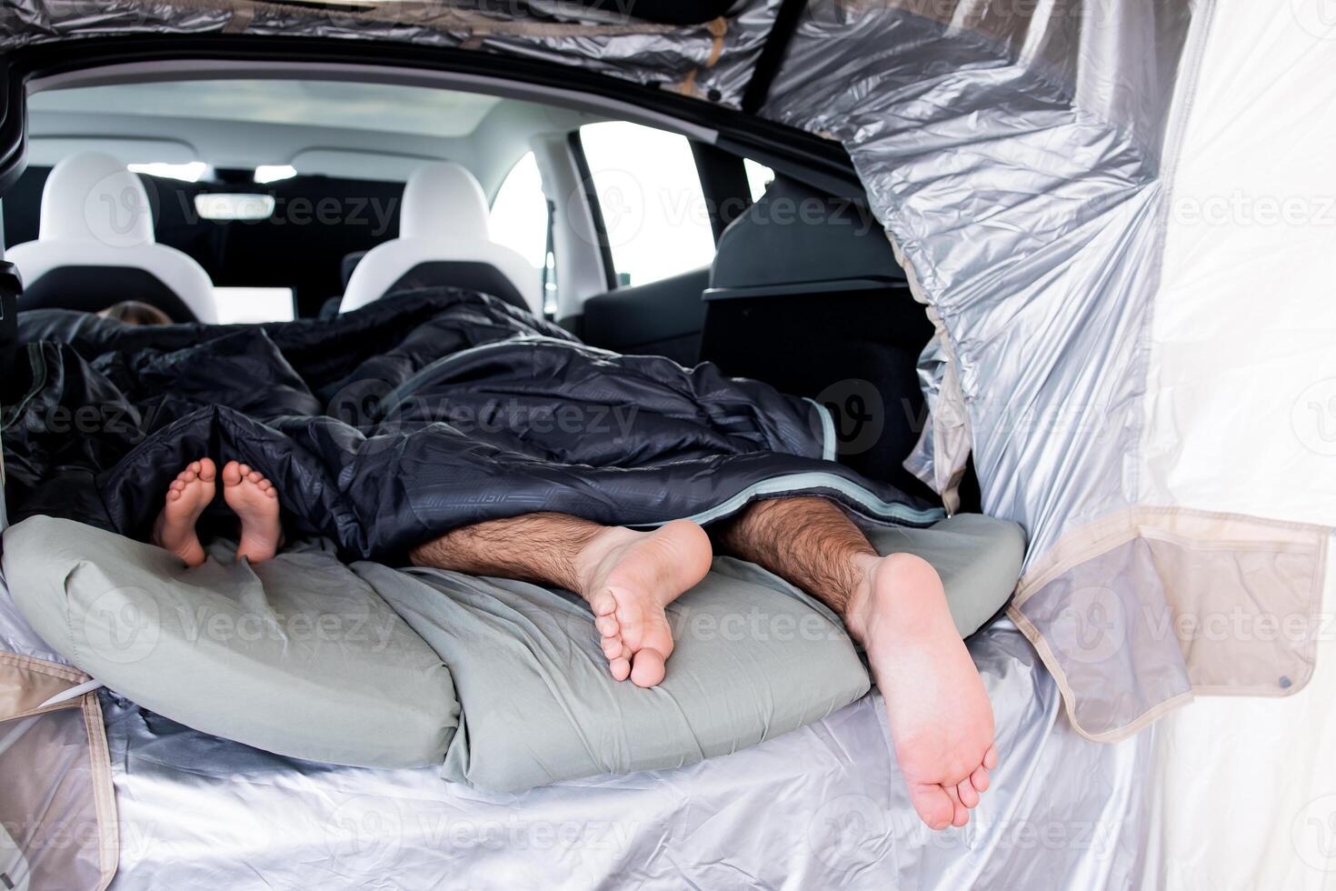Cozy car camping with family. Adults and child sleeping in car with sleeping bags photo