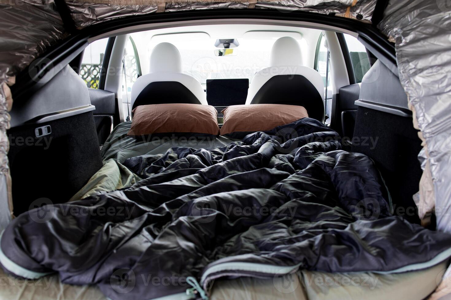 Cozy camping setup inside modern car with sleeping bag and pillows photo
