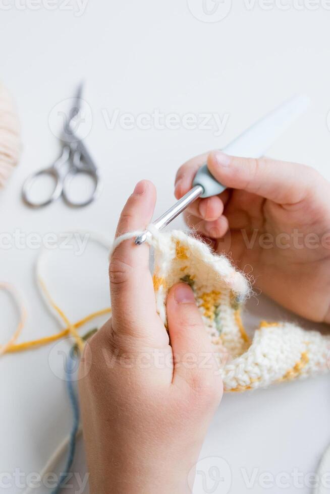 Close up of hands crocheting a colorful pattern with crochet hook and yarn photo