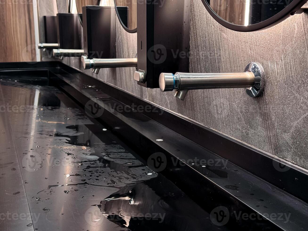 Modern bathroom sink with water spill and sleek metal fixtures photo