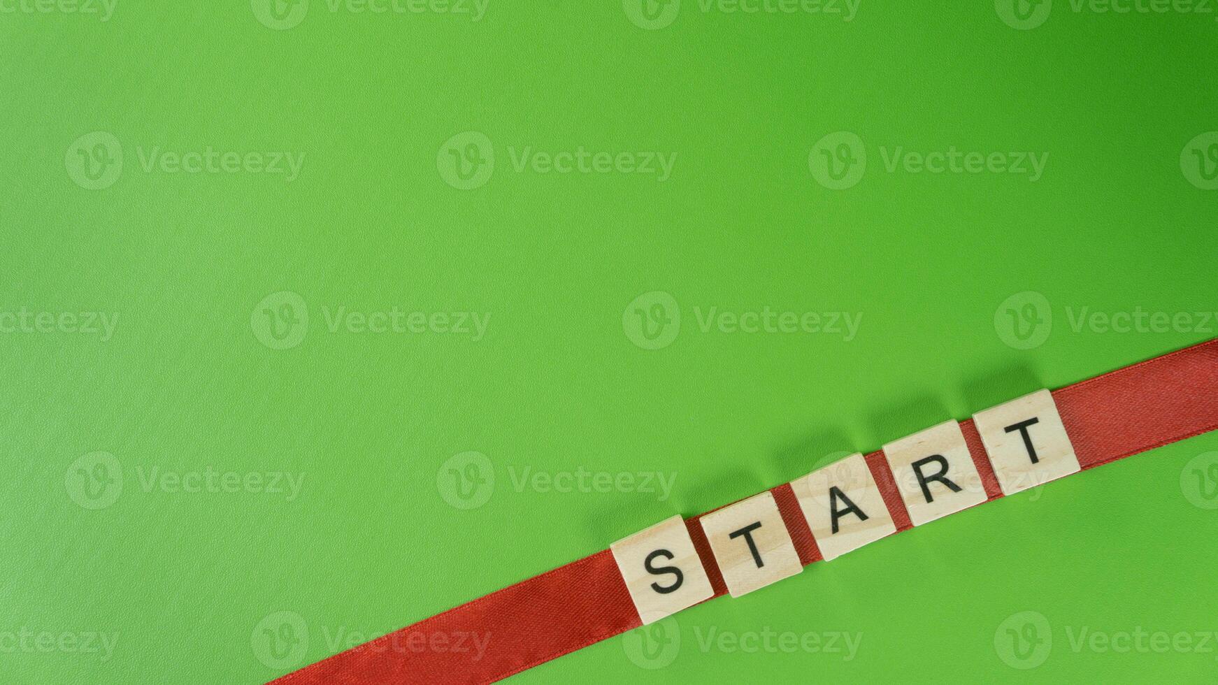 Diagonal Word START with Wooden Letter Tiles on Red Ribbon and Green Background Motivation and Beginning Concept photo