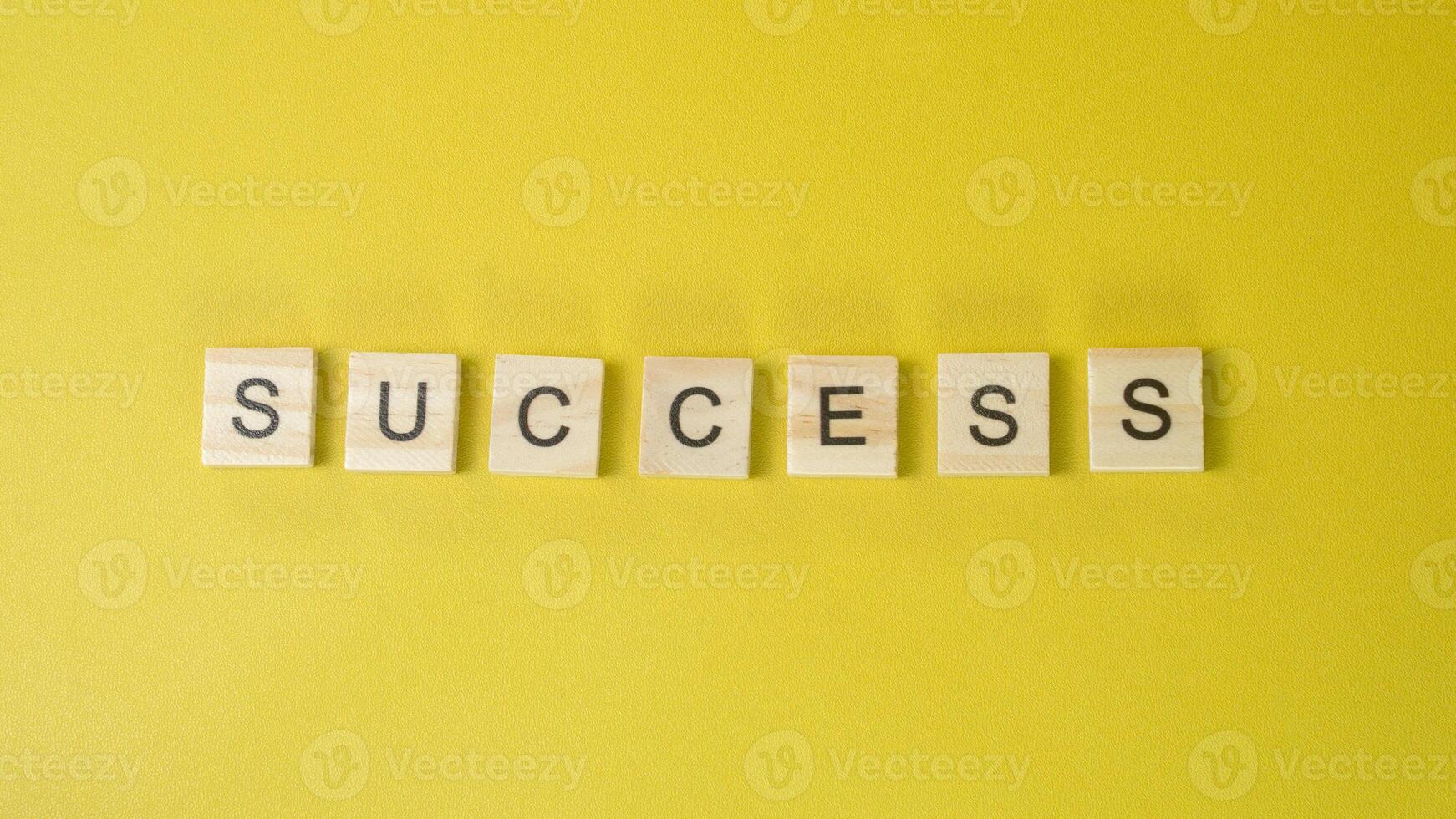 Word SUCCESS Built with Wooden Tiles on Yellow Background Career Goal and Motivation Theme photo