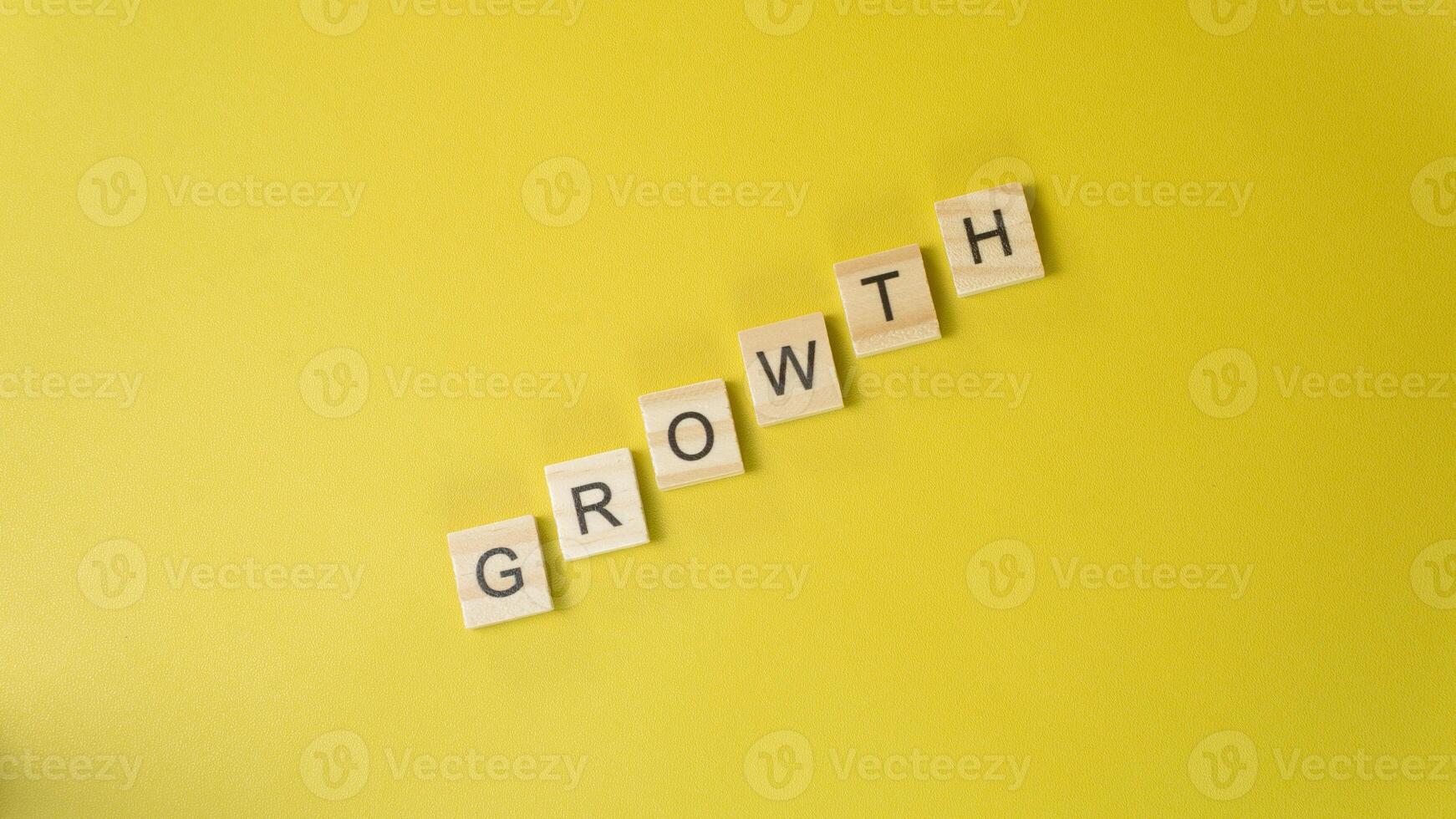 Wooden Letters Spelling GRsOWTH Diagonally on Yellow Background Personal Development and Progres photo